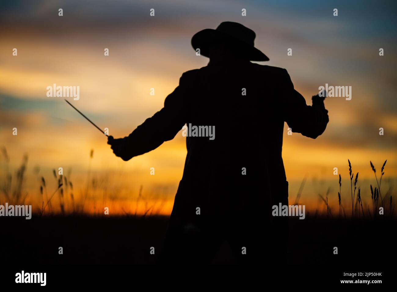 Silhouette di un demone e cacciatore di vampiri con un cielo spettacolare sullo sfondo. Un uomo con un katana e un revolver. Fantasia e concetto di Halloween Foto Stock