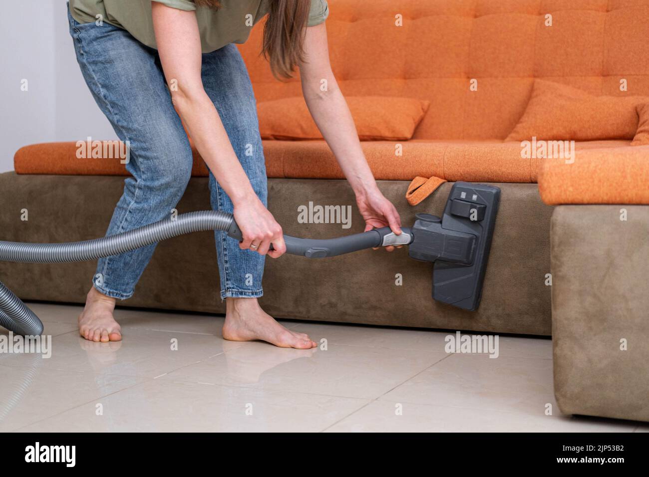 La giovane donna che pulisce in casa, aspirando il divano, il lavoro di casa, la famiglia pulisce la stanza a casa. Foto Stock