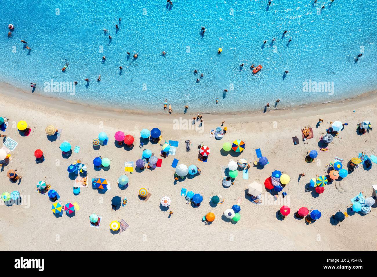 Vista aerea di ombrelloni colorati sulla spiaggia di sabbia, persone in mare blu al tramonto in estate. Spiaggia di Tuerredda, Sardegna, Italia. Paesaggio tropicale con tu Foto Stock