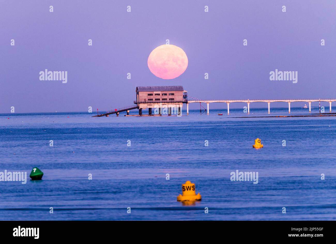 Sturgeon Luna piena che sale sopra capannone e molo Foto Stock
