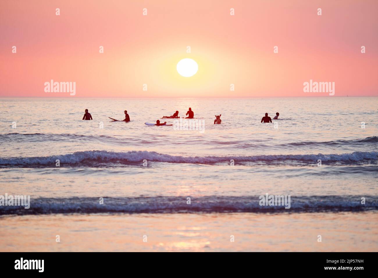 Surfers in attesa di onde al tramonto. Cornovaglia, Inghilterra Foto Stock