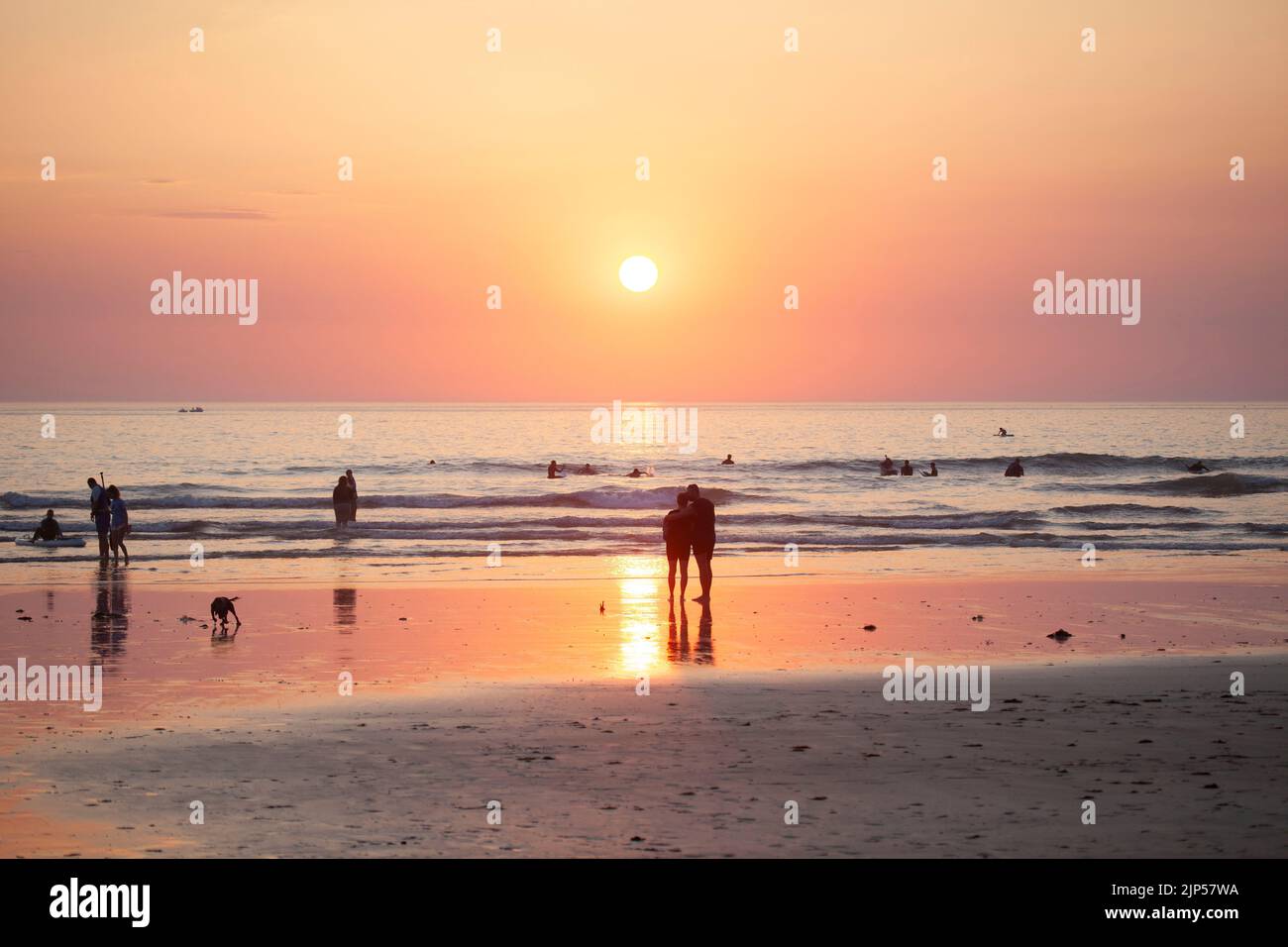 Coppia che guarda il tramonto. Polzeath spiaggia. Cornovaglia, Inghilterra Foto Stock