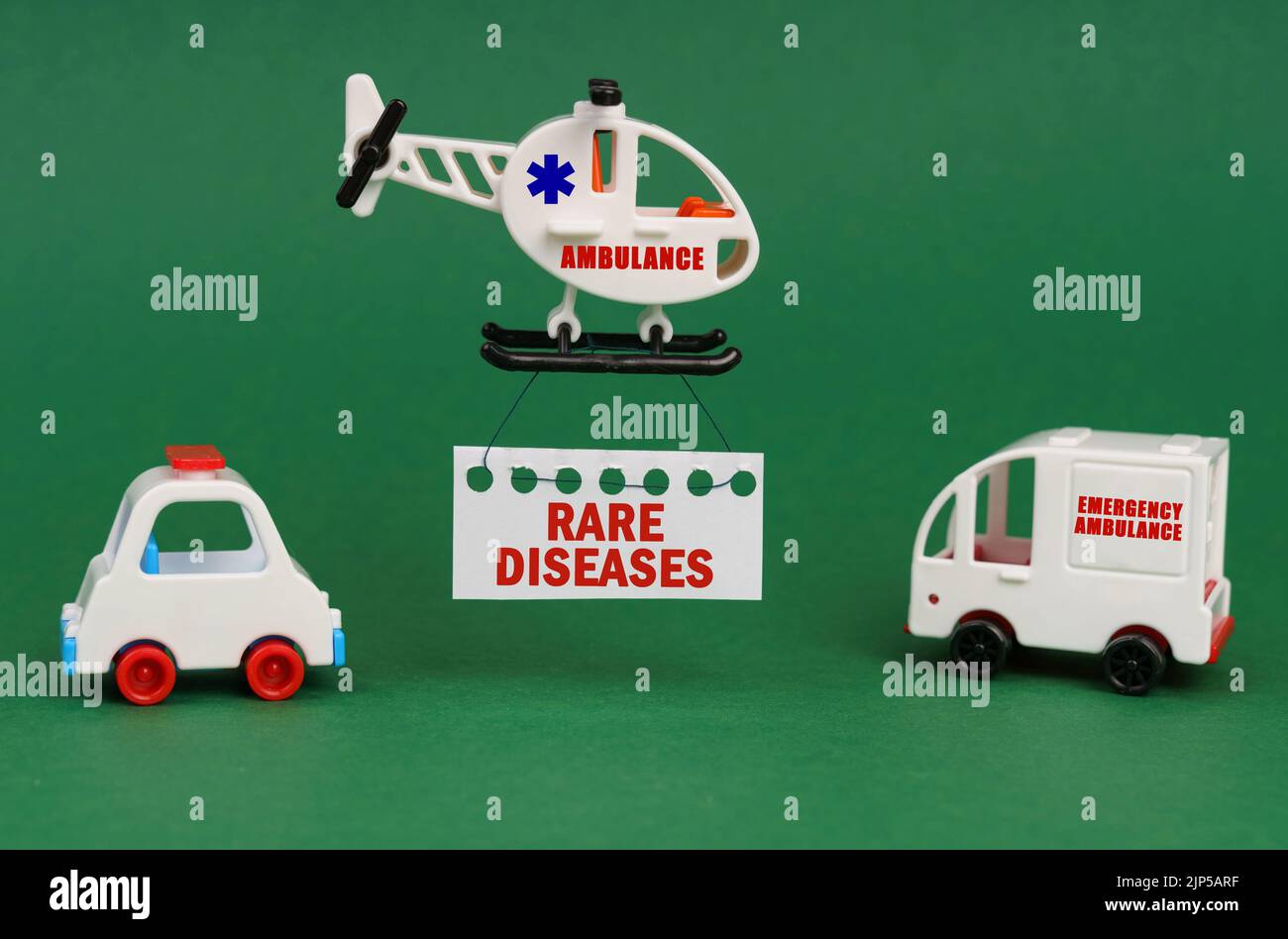 Concetto medico. Su una superficie verde, auto e un elicottero ambulanza con un segno - MALATTIE RARE Foto Stock
