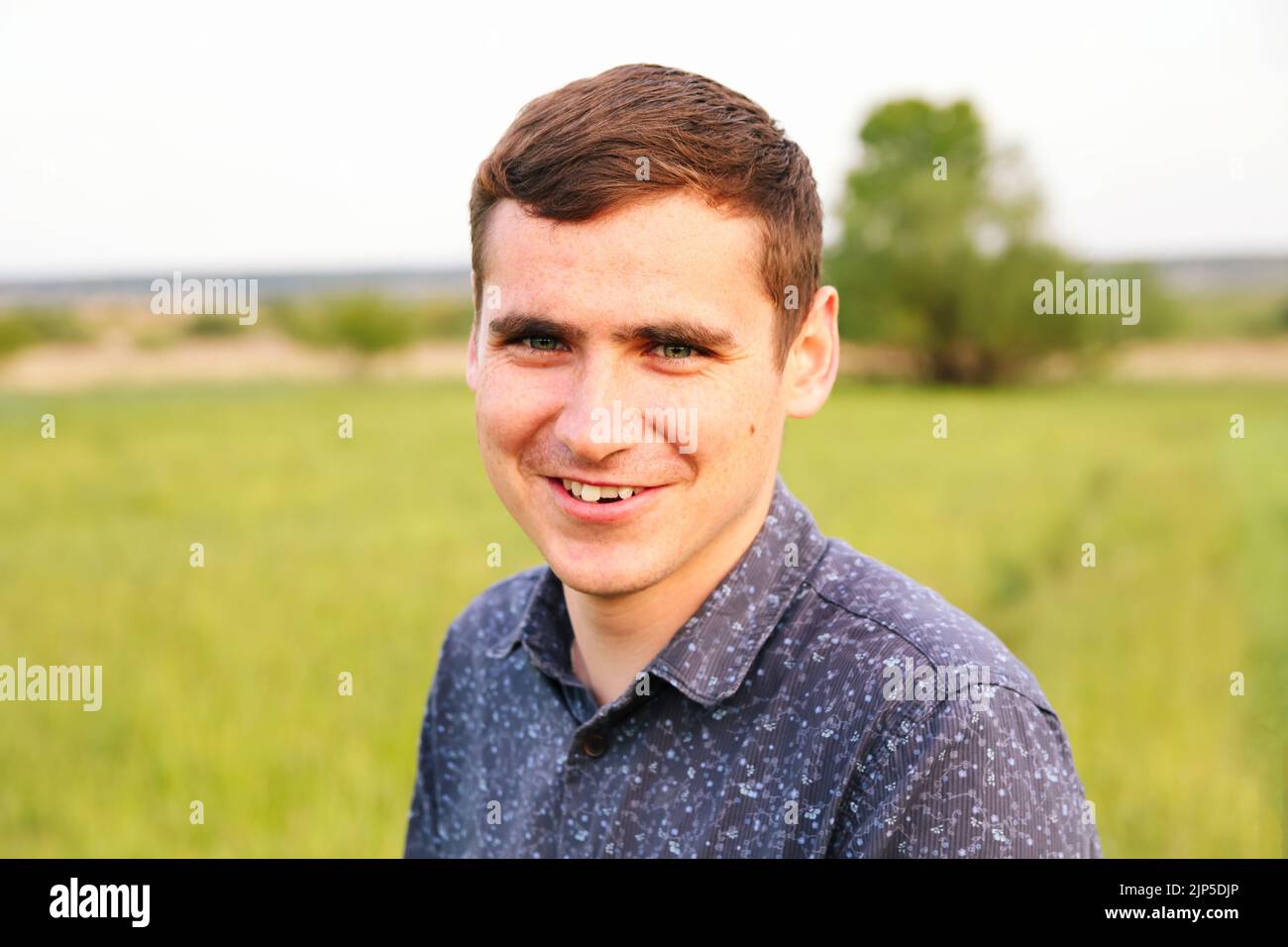 Defocalizzazione ritratto giovane uomo sulla natura sfondo estate. Giovane uomo sorridente. 20s anni. Bel ritratto uomo all'aperto. Passeggiate nel parco. Stile di vita Foto Stock