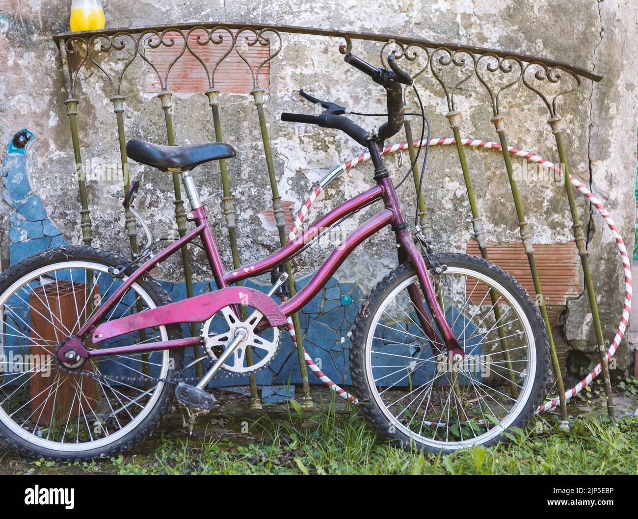 foto della bicicletta della vecchia ragazza appoggiata su una ringhiera arrugginita e sul cerchio del gioco Foto Stock