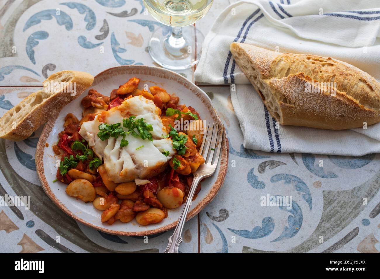 Piatto spagnolo di merluzzo con fagioli al burro, pomodori e chorizo Foto Stock