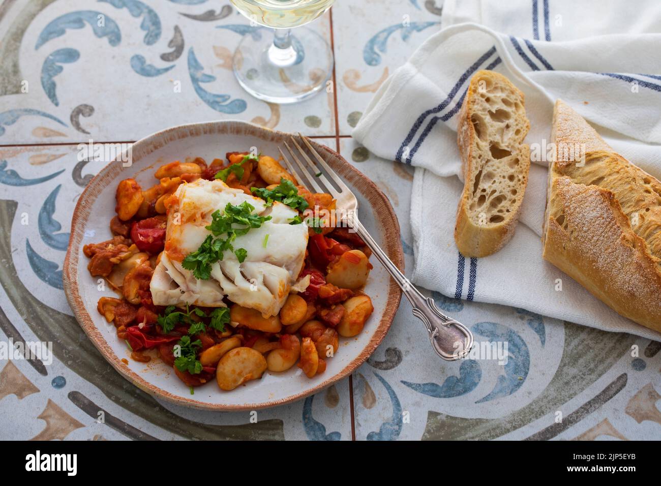 Piatto spagnolo di merluzzo con fagioli al burro, pomodori e chorizo Foto Stock