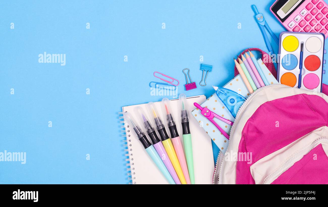 Zaino da scuola con cancelleria e strumenti di scrittura su sfondo blu pastello. Spazio di copia a giacitura piatta Foto Stock