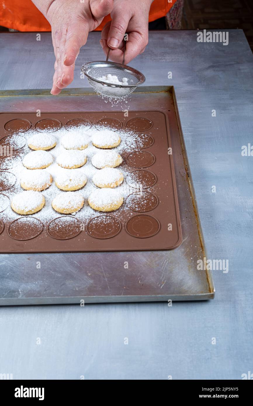 Pasticciere cospargere lo zucchero sui dolci da sposa su un piatto di silicone marrone_foto verticale. Foto Stock