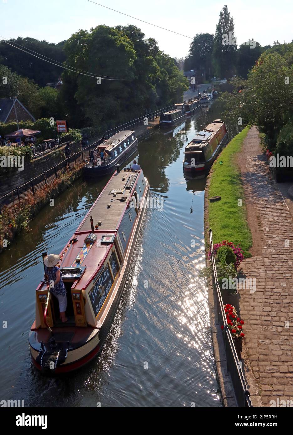 Il Barge Juggler dal bacino di Glascote, passa attraverso il villaggio di Lymm sul canale di Bridgewater, Warrington, Cheshire, Inghilterra, Regno Unito, WA13 0HR Foto Stock
