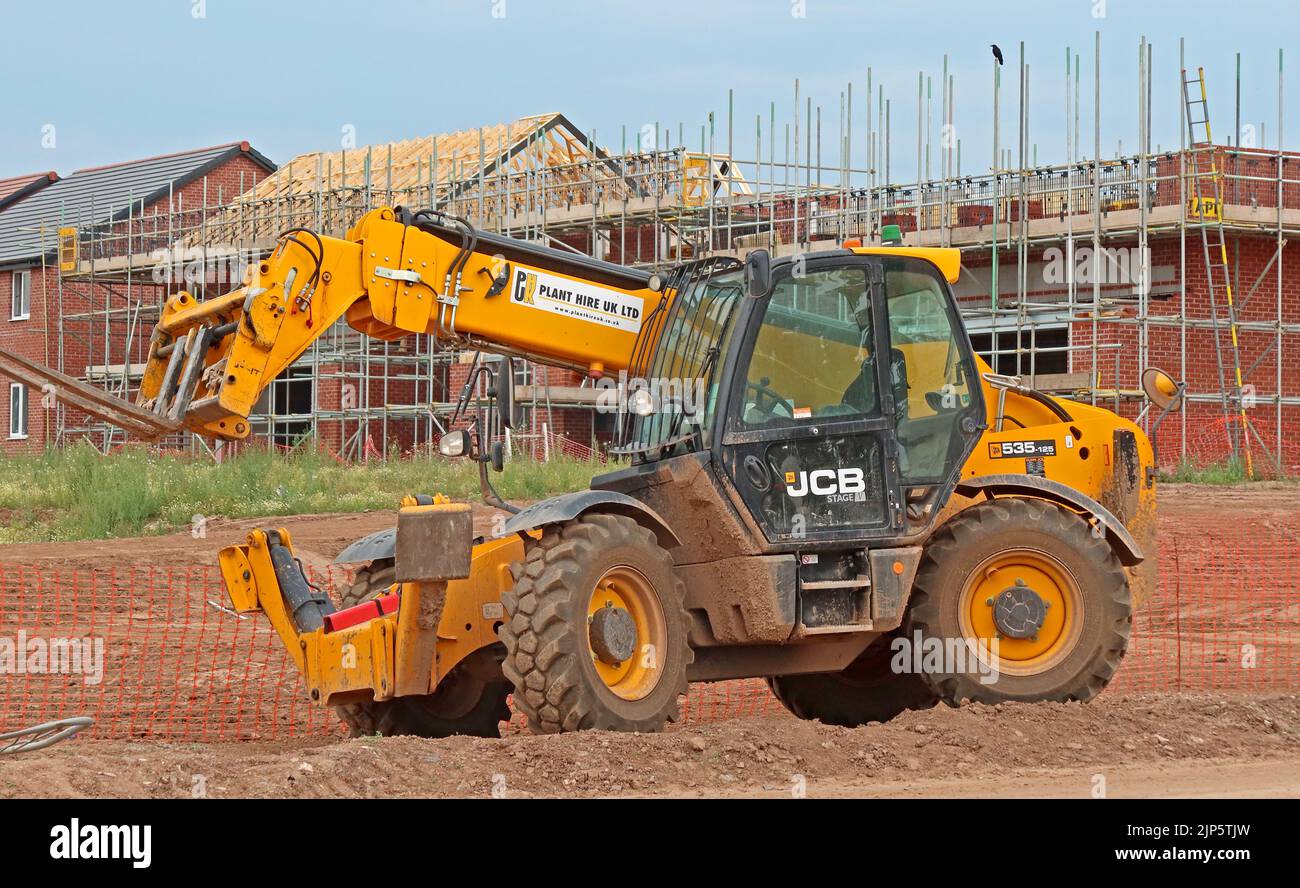 Cantiere di sviluppo - JCB 535-125 costruzione movimentatore telescopico Loadall che opera di fronte a nuove proprietà circondate da ponteggi Foto Stock