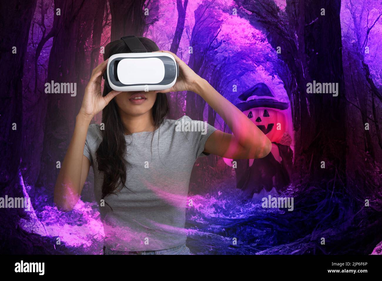 Donna che utilizza la tecnologia della fotocamera 3D gode di simulazione virtuale di halloween incubo nella foresta. Foto Stock