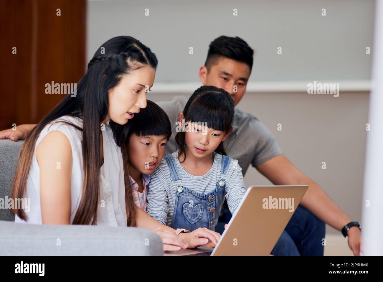 Online è dove trovano intrattenimento per tutti. Una famiglia che utilizza un notebook insieme a casa. Foto Stock