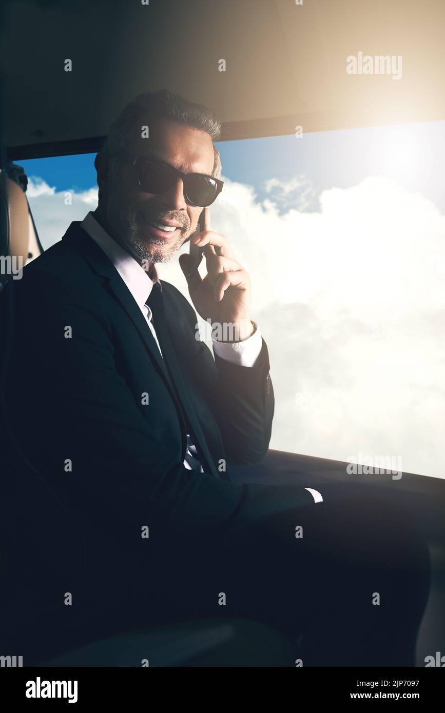 Vai in grande o Vai a casa. un uomo d'affari maturo utilizzando un telefono cellulare mentre si viaggia in elicottero. Foto Stock