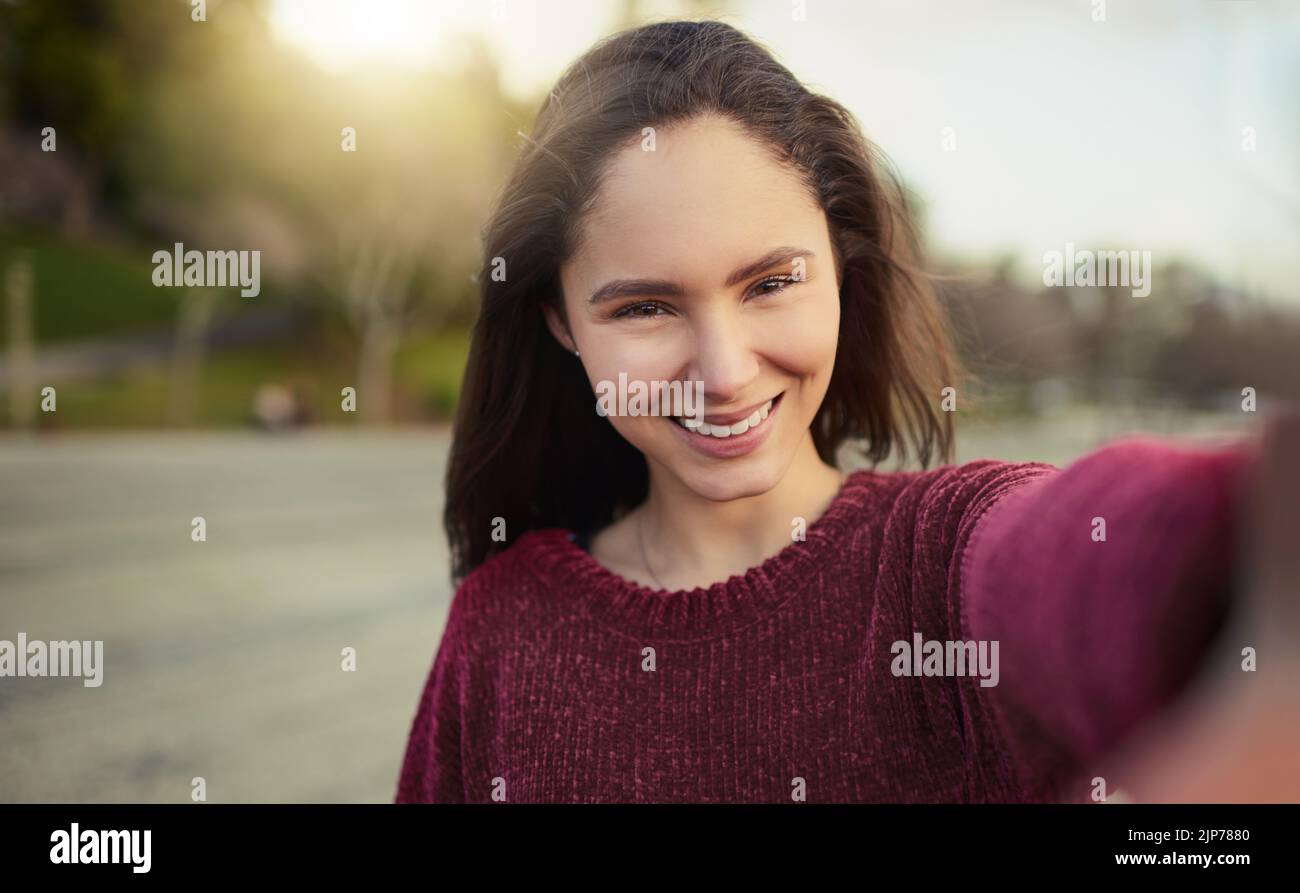 Passare la giornata solo me da myselfie. Ritratto di una giovane donna felice che prende un selfie all'aperto. Foto Stock