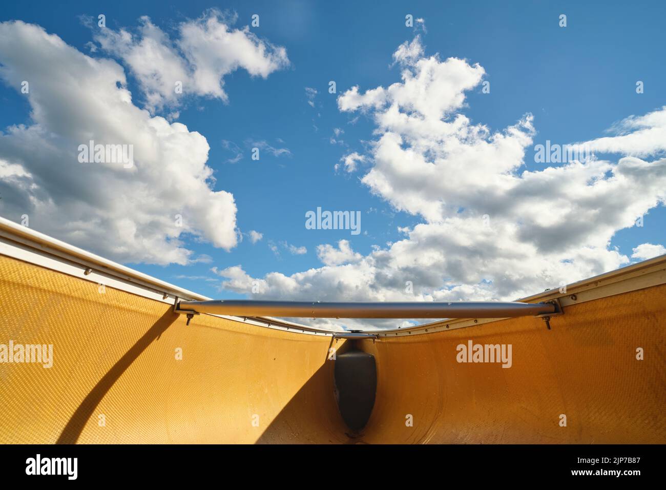 Una vista dal basso nello scafo di una canoa mostra un cielo blu con soffici nuvole bianche sopra la prua della canoa. Foto Stock