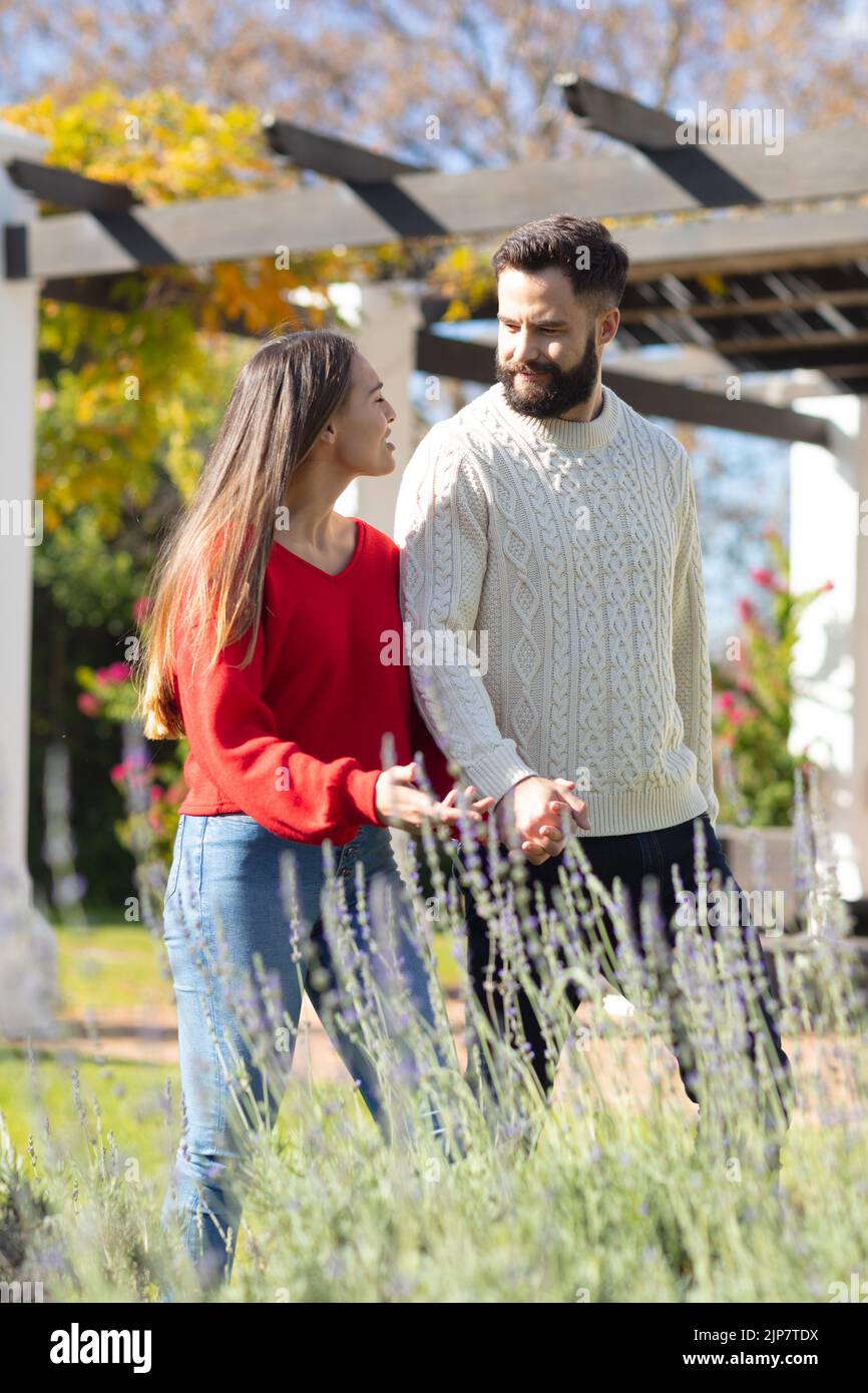 Felice coppia caucasica a piedi in giardino, tenendo le mani e parlando Foto Stock