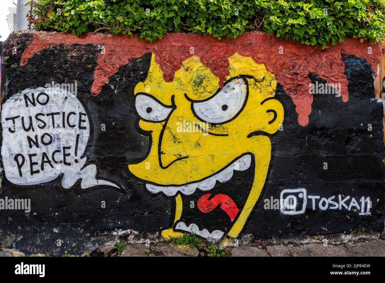 Un primo piano di graffiti "No justice no peace" su un muro a Trafalgar Lane, Brighton, Inghilterra Foto Stock