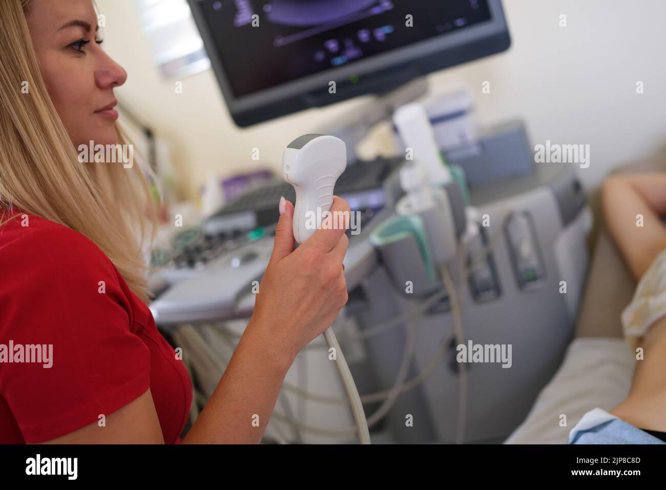 Medico donna che tiene il trasduttore a ultrasuoni e che esamina la paziente di sesso femminile Foto Stock