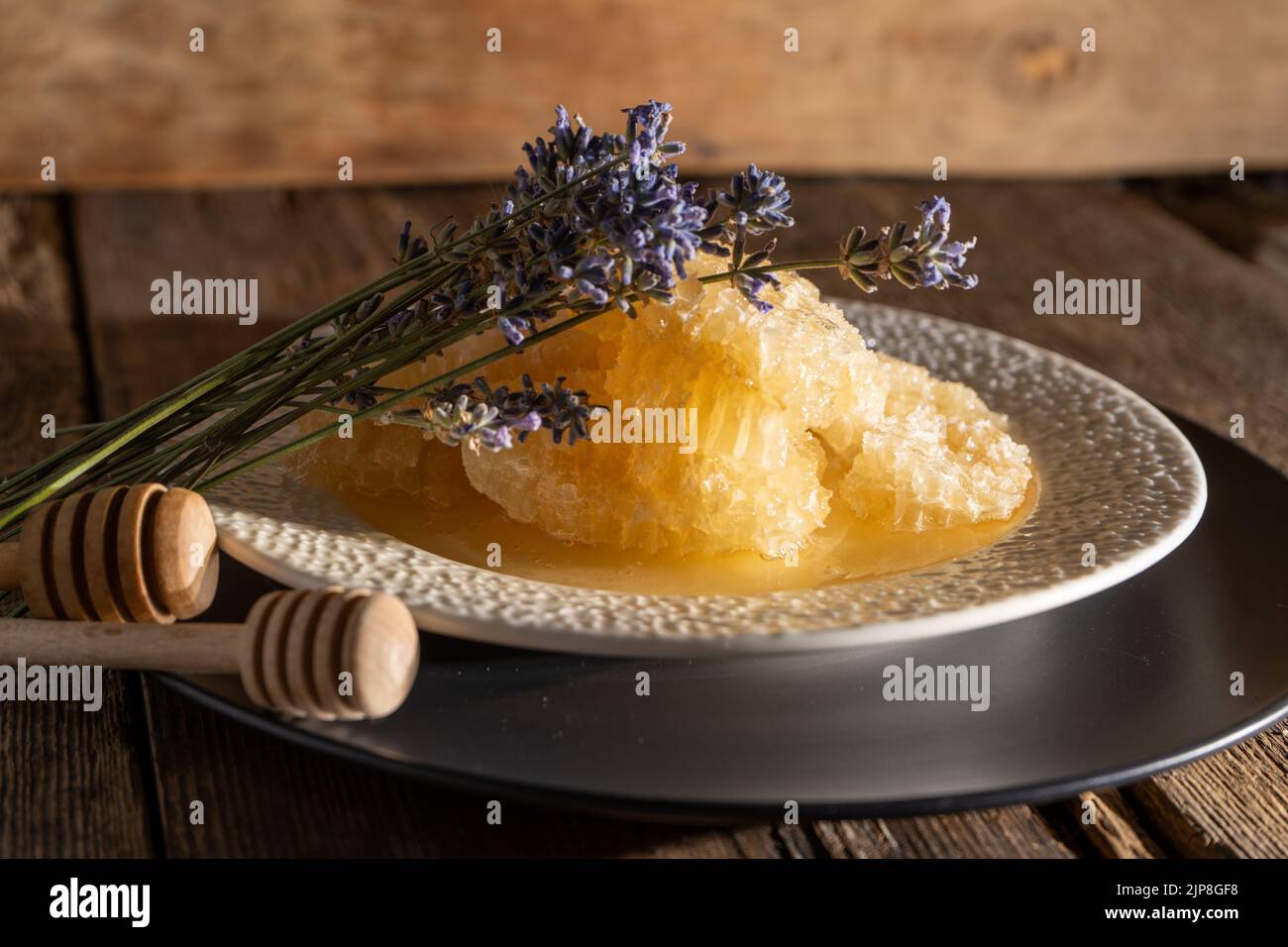 Miele e nido d'ape su un piatto bianco. Cibo dolce in una ciotola sul tavolo. Un prodotto dell'apicoltura. Fiore di lavanda. Foto Stock