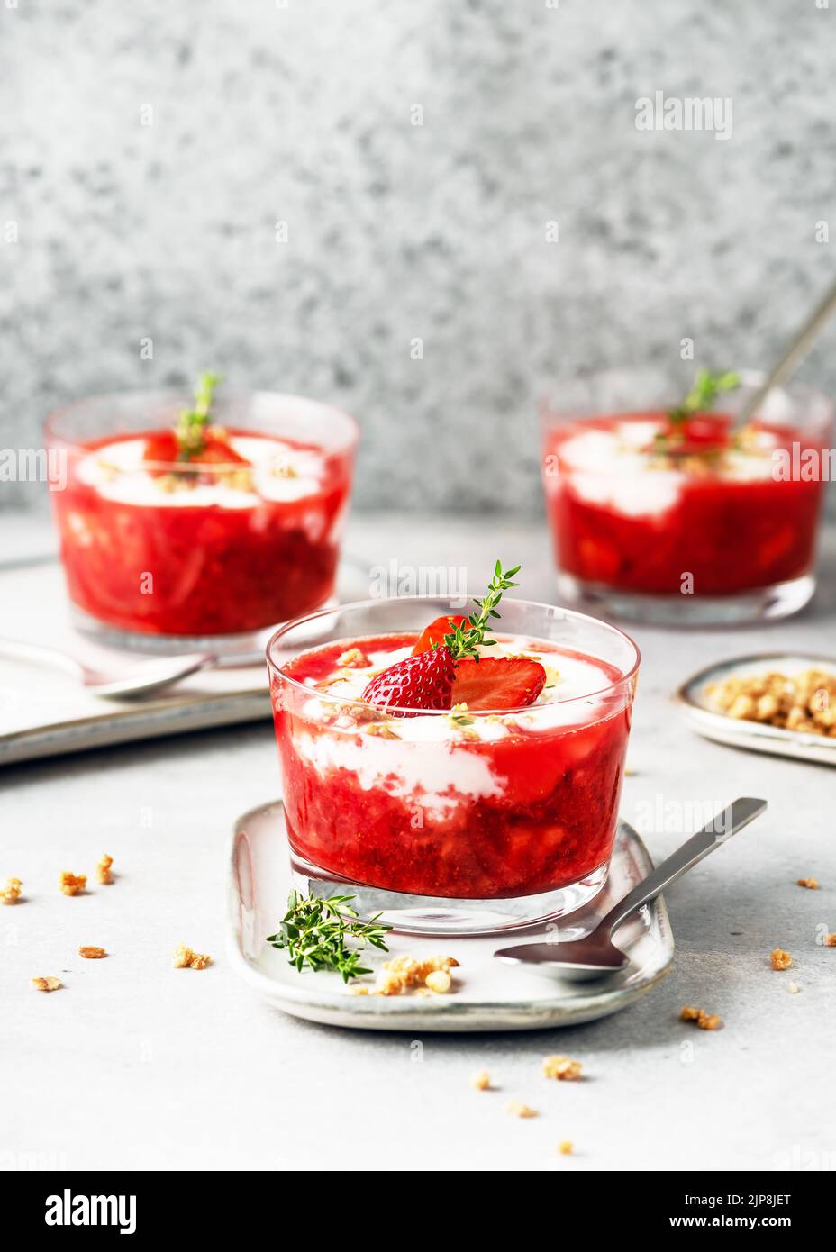 Purea di fragole dolci e dessert al formaggio cremoso decorato con frutti di bosco freschi, muesli e rametti di timo in bicchieri. Concetto di cibo sano fatto in casa. Foto Stock