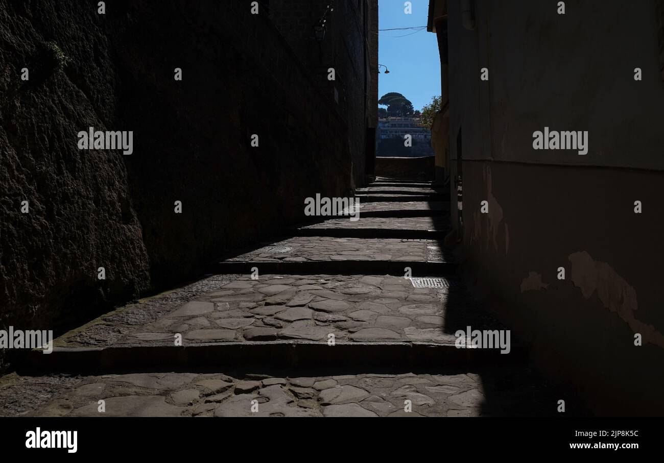 Stradina ciottolata stretta di Sorrento vicino a Marina Grande scatto suggestivo con il sole che cade sulla strada e ombra edifici circostanti. Foto Stock