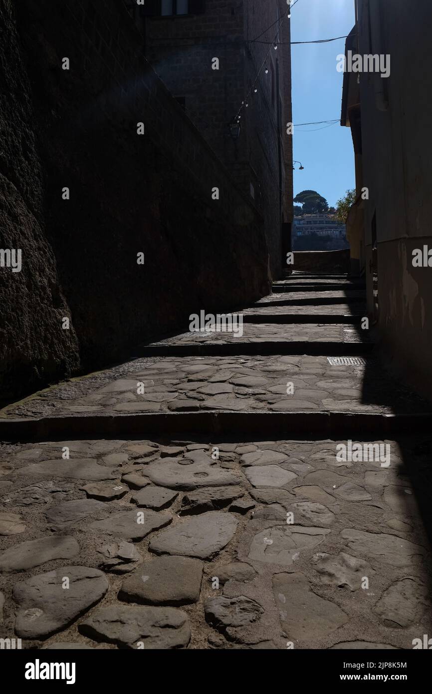 Stradina ciottolata stretta di Sorrento vicino a Marina Grande scatto suggestivo con il sole che cade sulla strada e ombra edifici circostanti. Foto Stock