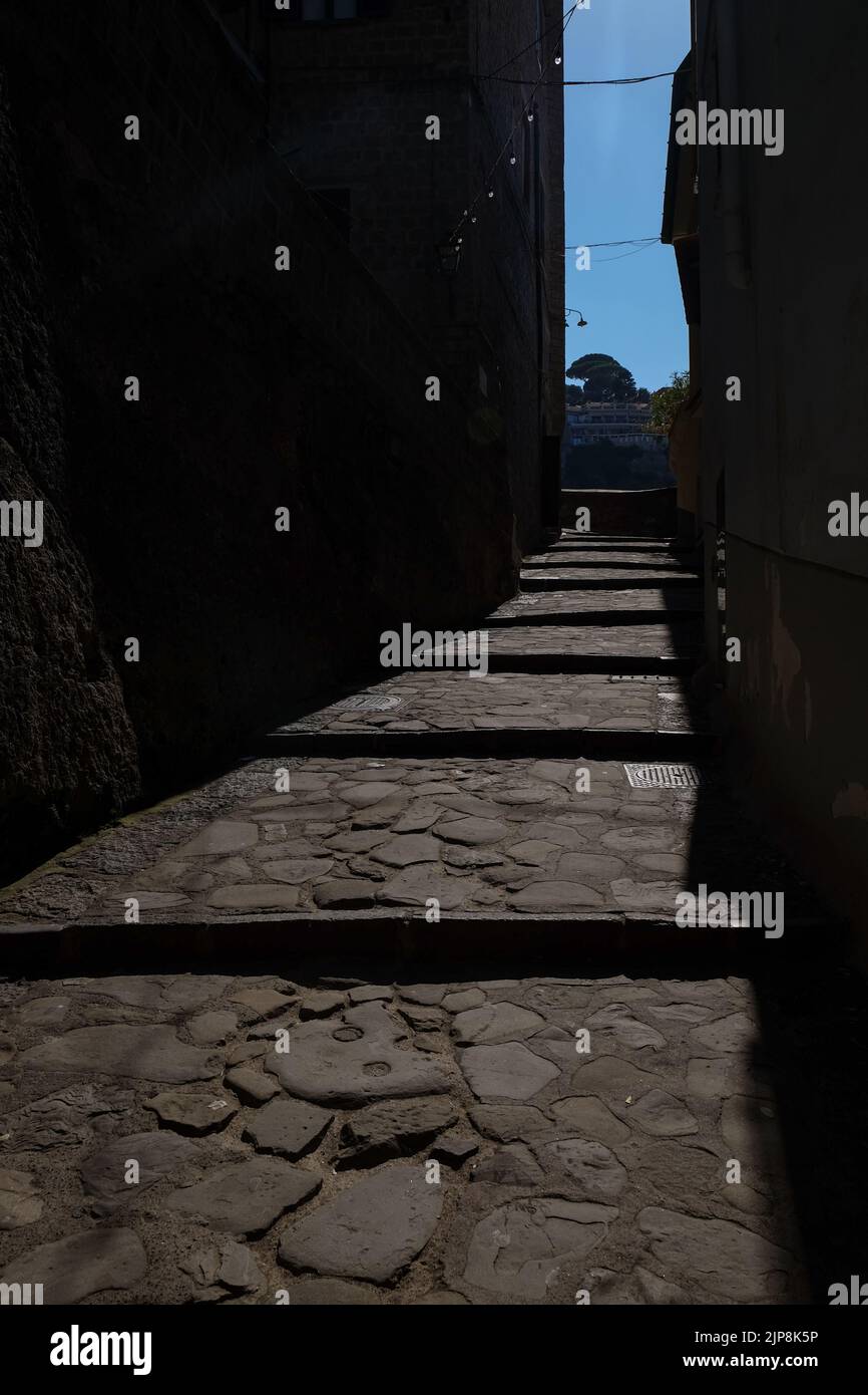 Stradina ciottolata stretta di Sorrento vicino a Marina Grande scatto suggestivo con il sole che cade sulla strada e ombra edifici circostanti. Foto Stock