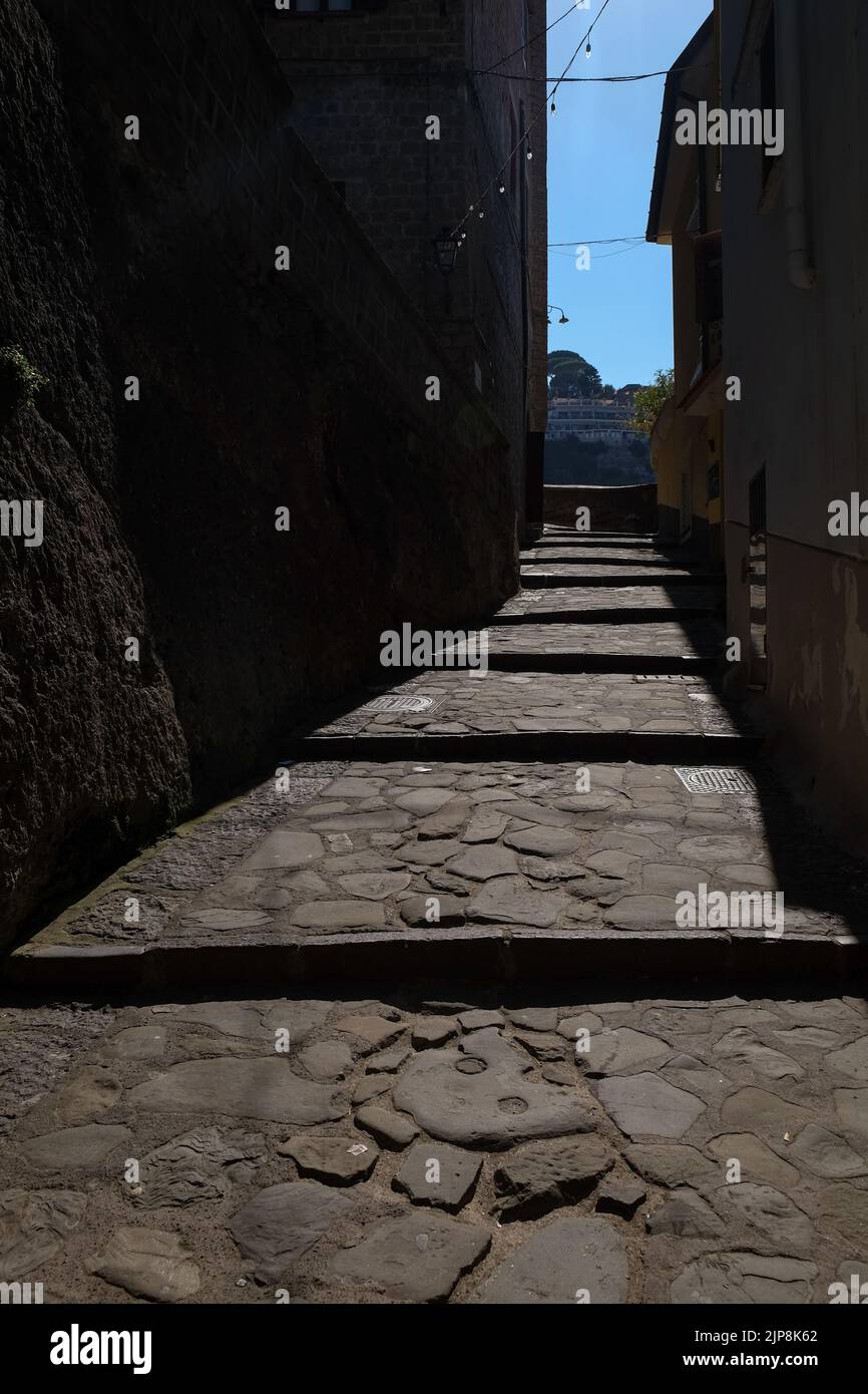 Stradina ciottolata stretta di Sorrento vicino a Marina Grande scatto suggestivo con il sole che cade sulla strada e ombra edifici circostanti. Foto Stock