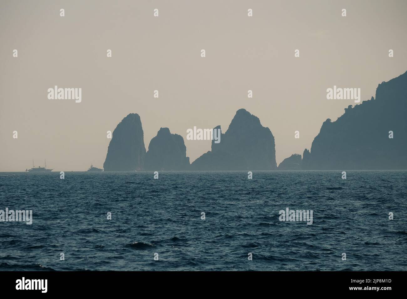 Capri faraglioni Wave erosione formazioni rocciose stagni dell'isola di Capri Italia nella baia di Napoli vista nella nebbia marina con barche da diporto. Foto Stock