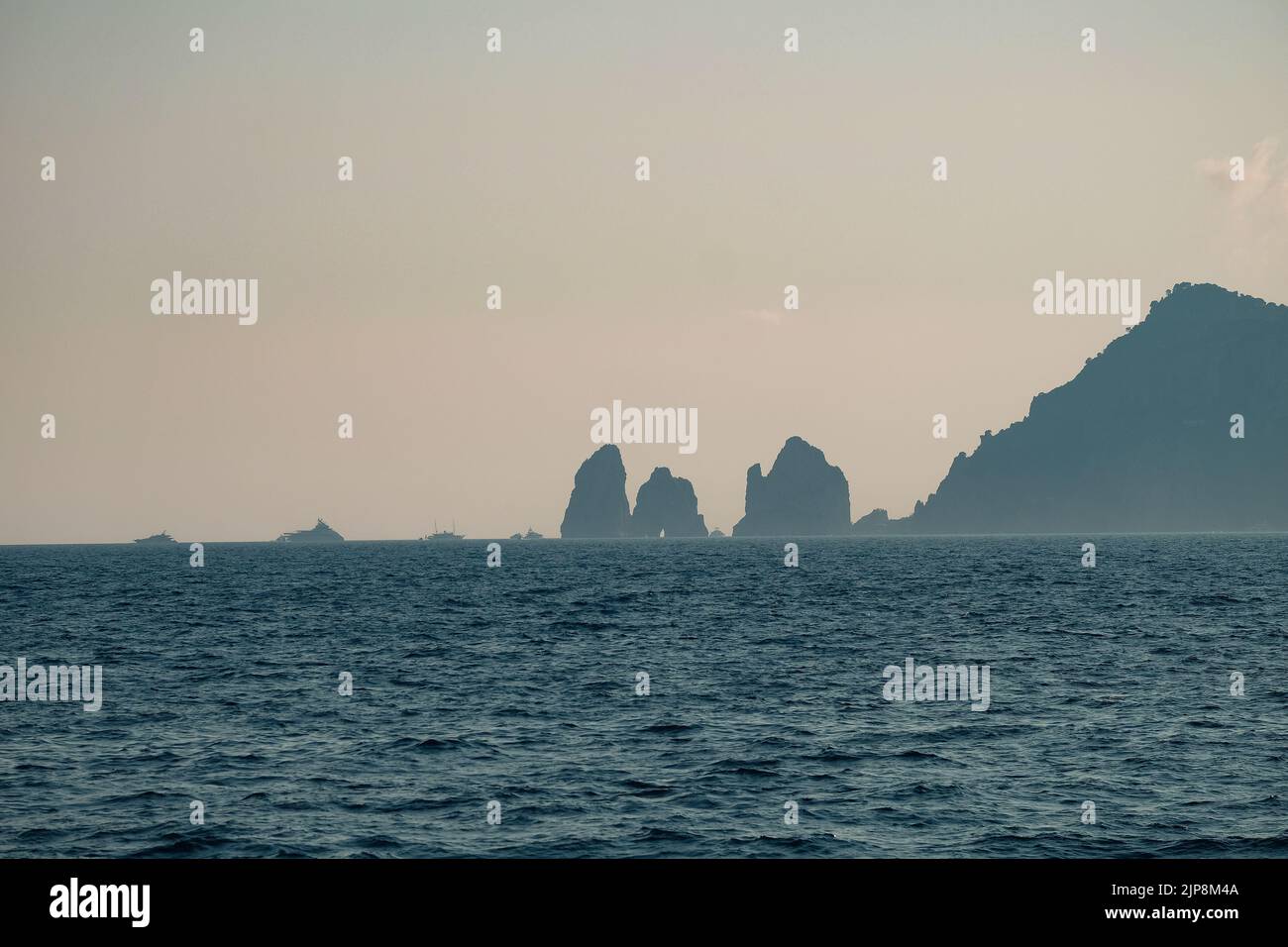 Capri faraglioni Wave erosione formazioni rocciose stagni dell'isola di Capri Italia nella baia di Napoli vista nella nebbia marina con barche da diporto. Foto Stock