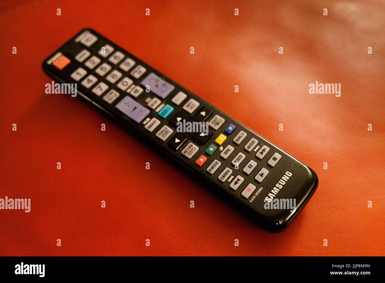 Un ricevitore nero usato del telecomando della televisione domestica Samsung su uno sfondo rosso Foto Stock