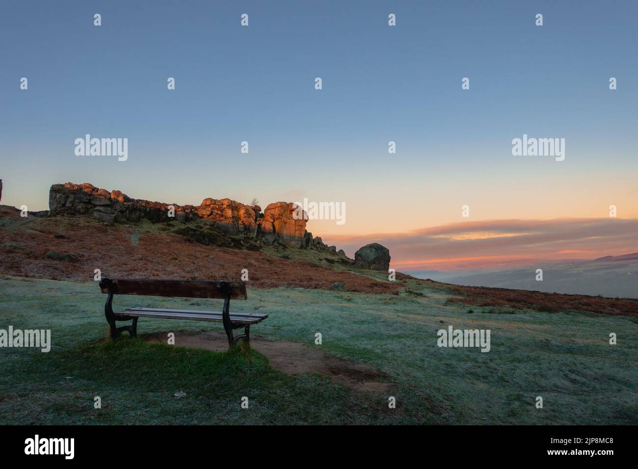 Paesaggi del Regno Unito: La panchina perfetta per essere in per l'ora d'oro e per guardare l'alba sulle rocce di Cow e Calf, Ilkley Moor, Inghilterra. Foto Stock