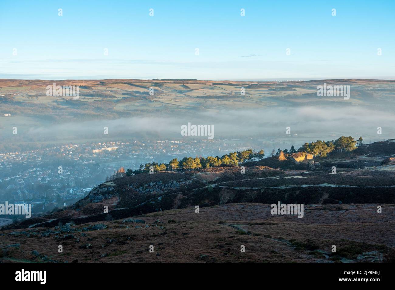 La mattina presto guardando la città di Ilkley da Ilkley Moor con una leggera nebbia appesa nella valle, West Yorkshire, Inghilterra. Foto Stock