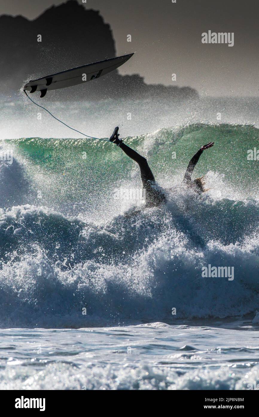 Un surfista che perde equilibrio e si sta spazzando via a Fistral a Newquay in Cornovaglia nel Regno Unito. Foto Stock
