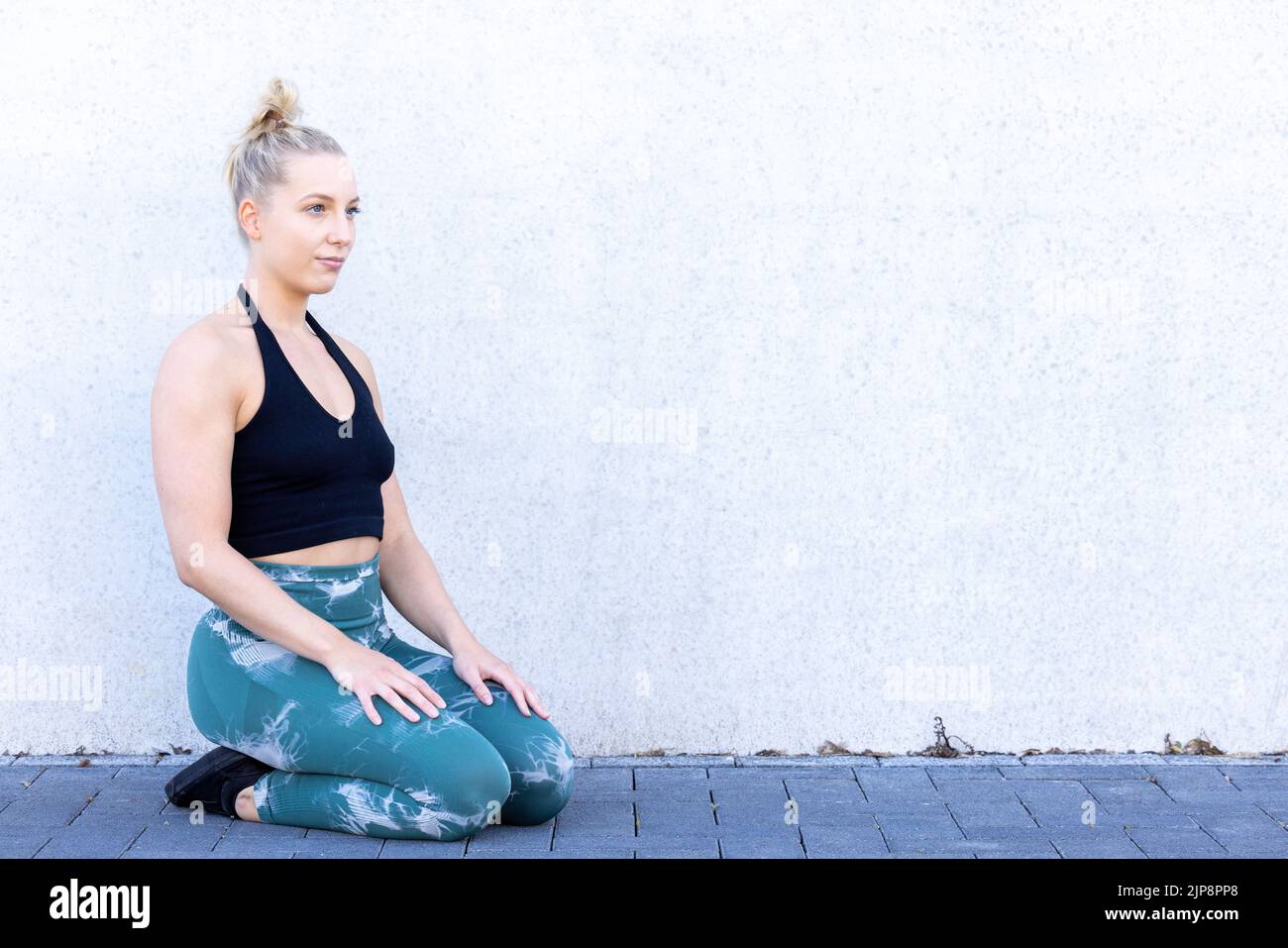 La giovane bionda caucasica sportiva che indossa abbigliamento sportivo nero e blu utilizza il telefono cellulare nel centro fitness. Le donne che giocano a videogame sullo smartphone in palestra. Le ragazze sportive che si trovano in un centro benessere dopo l'allenamento si allenano. Foto di alta qualità Foto Stock