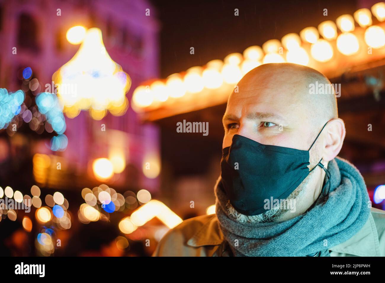 adulto che indossa la maschera all'aperto in una fiera di natale della città di notte Foto Stock