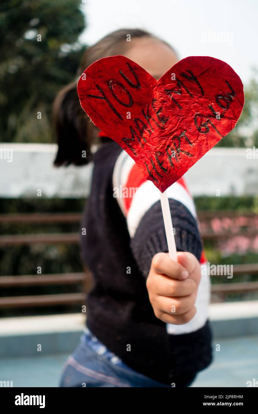 Febbraio 14th 2021. Dehradun India. Buon San Valentino. Un capretto indiano carino che tiene la scheda rossa a forma di cuore con una citazione d'amore 'il vostro Make My Heart Foto Stock