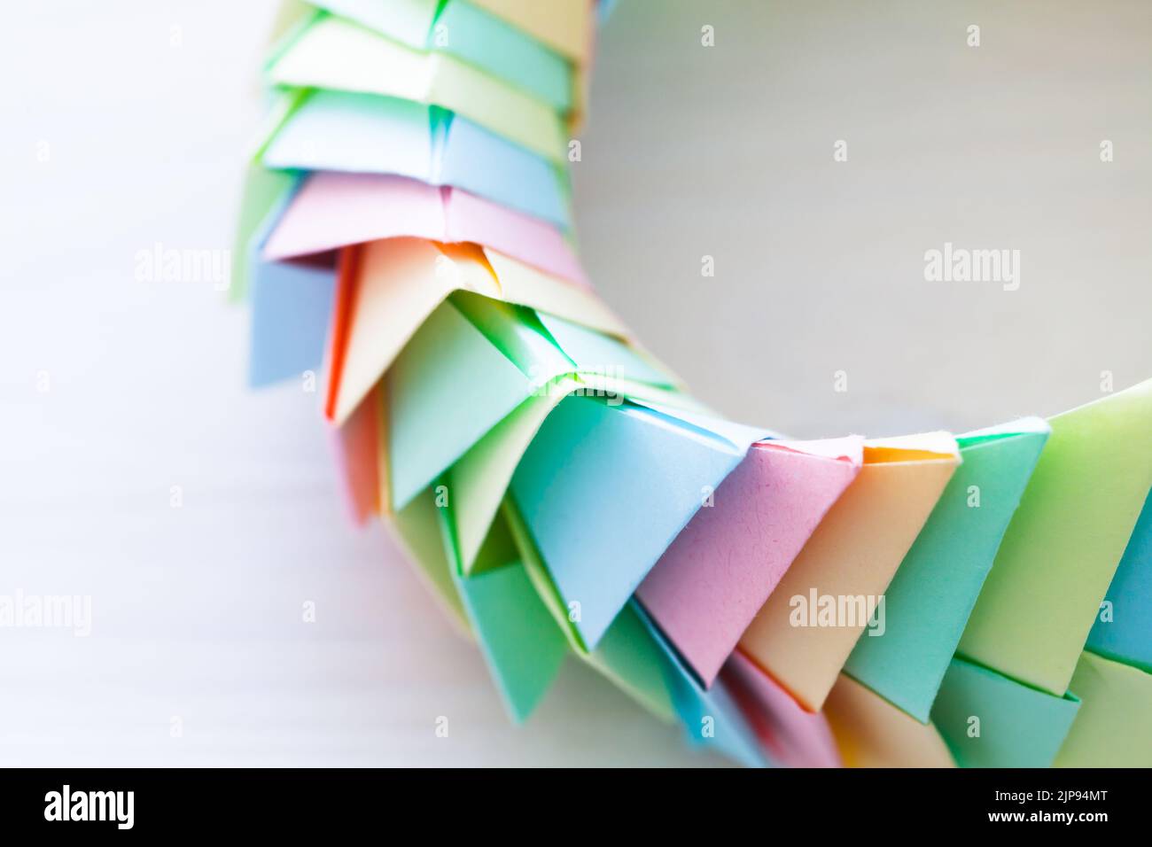 Frammento di un anello origami adagiato su sfondo bianco, struttura parametrica astratta in fogli di carta colorati, vista dall'alto. Foto ravvicinata con l' Foto Stock