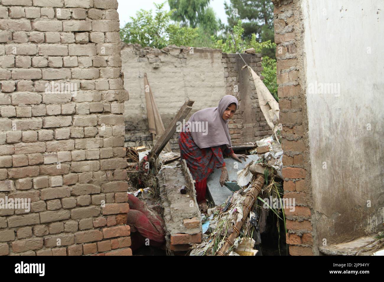 Nangarhar, Afghanistan. 15th ago, 2022. Una donna è vista in una casa distrutta da un'alluvione nella provincia di Nangarhar, Afghanistan, 15 agosto 2022. Almeno otto persone sono state uccise e altre sei sono state ferite lunedì a causa di forti piogge e inondazioni improvvise nella provincia orientale afghana di Nangarhar, ha dichiarato un funzionario locale. Credit: Aimal Zahir/Xinhua/Alamy Live News Foto Stock