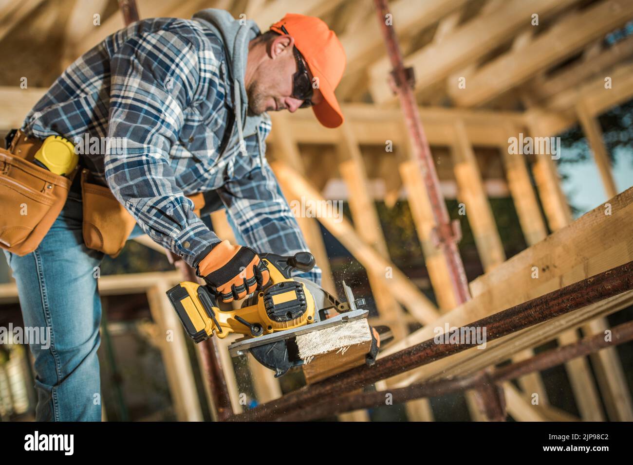 Caucasian Middle Aged Builder che lavora con l'elettroutensile elettrico per la levigatura del legno presso il cantiere di costruzione dello scheletro di legno di stile canadese residenziale B Foto Stock