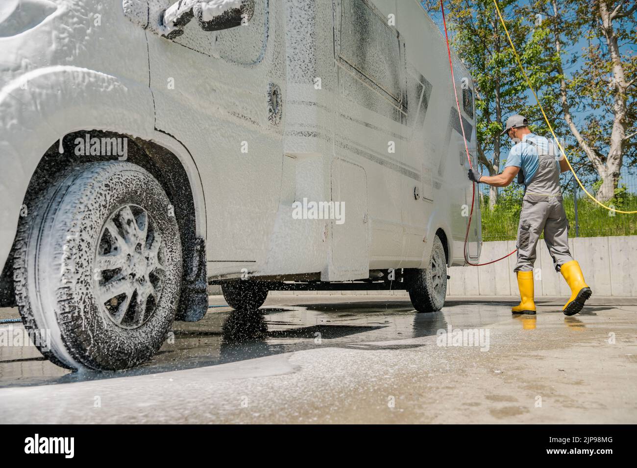 Uomo caucasico applicare la schiuma attiva durante il lavaggio del suo Camper Van a self-service pressione Car Wash. Motorhome cura e manutenzione tema. Foto Stock
