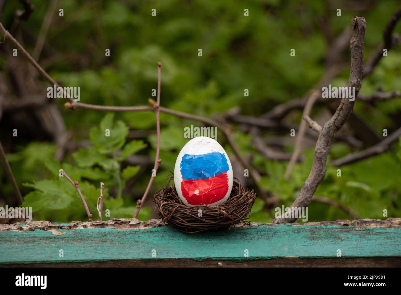 Un uovo bianco con una bandiera dipinta della Russia è rotto nelle mani di una donna, vacanza di Pasqua, la Russia è rotto e perso la guerra 2022 Foto Stock
