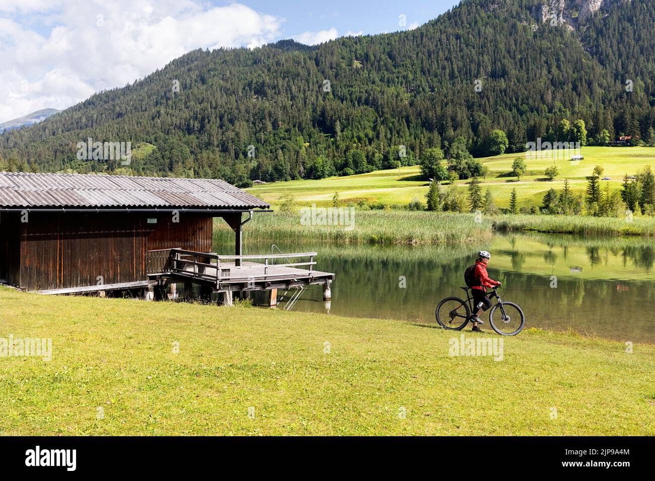 Ciclisti donne vicino a una tradizionale capanna di legno in una gita in bicicletta nel bellissimo lago Weissensee in Carinzia, in Austria Foto Stock