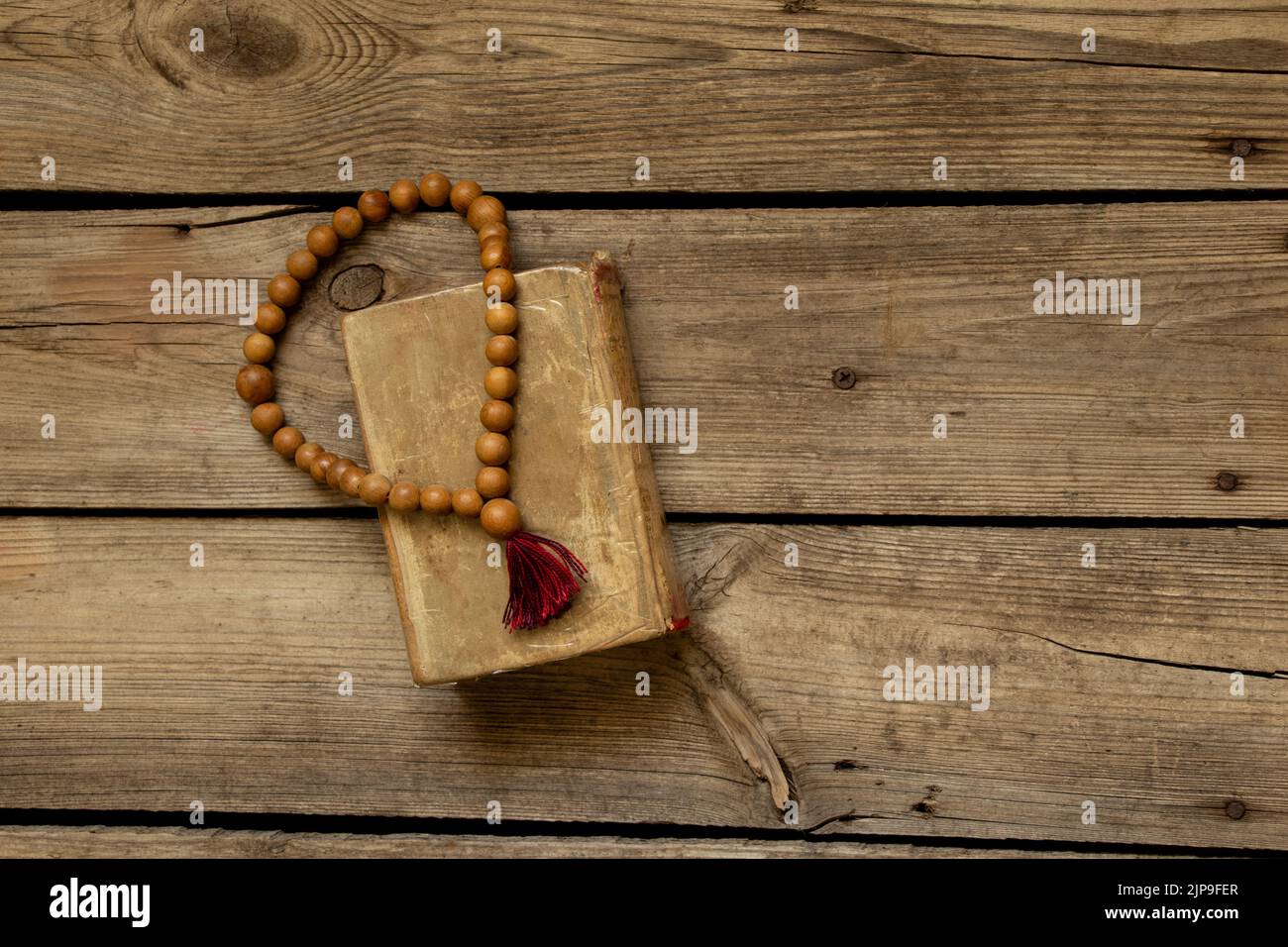 Il rosario di legno giace sulla bibbia su una tavola di legno, la bibbia e la religione, la fede e Dio Foto Stock