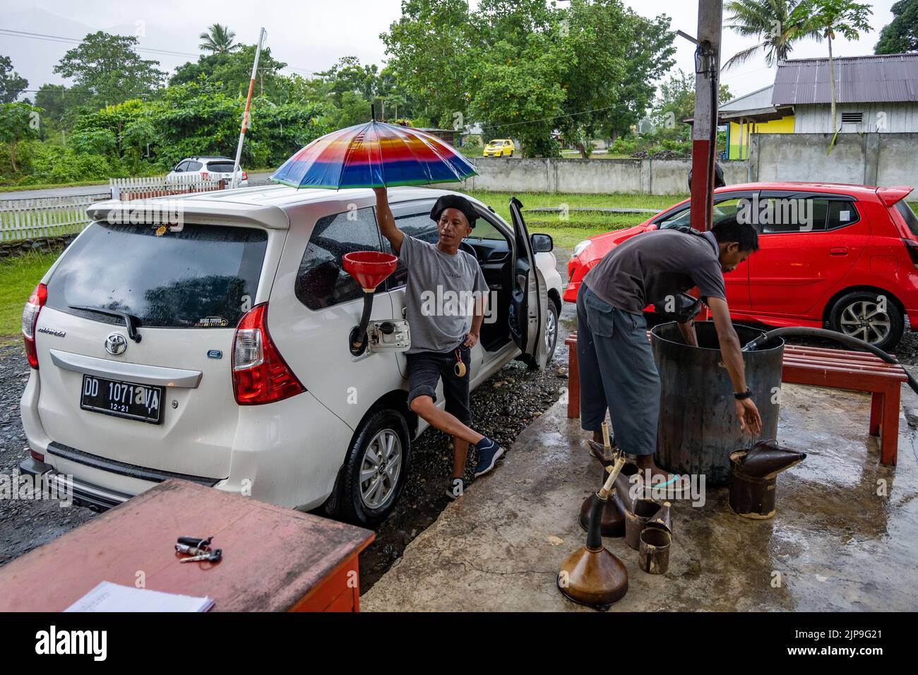 Due uomini riempiono un'auto in una stazione di servizio make-shift. Halmahera, Indonesia. Foto Stock