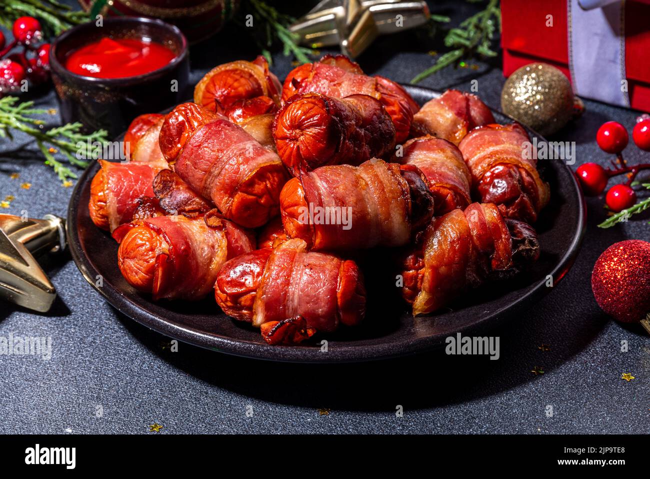 Piatto di Natale tradizionale ricetta maiali in coperte, salsicce avvolti in pancetta, forno di pasta sfoglia hot dog panini con rami d'albero di Natale, decorati Foto Stock