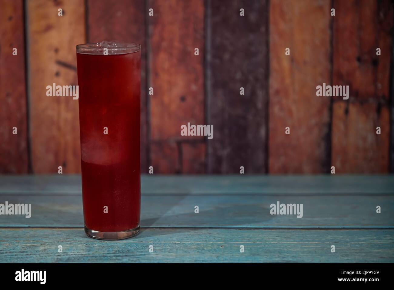Rosso estate. Vino rosso con bicarbonato di limone e molto ghiaccio in un bicchiere alto su un tavolo di legno. Foto Stock