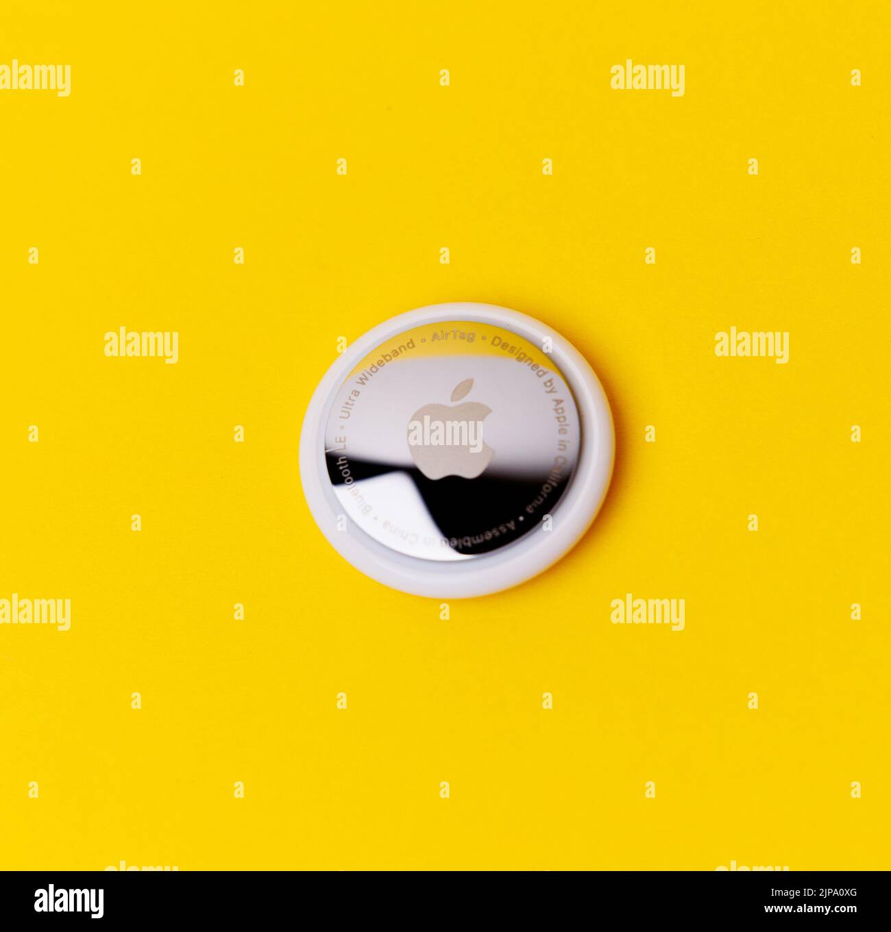 Un Apple AirTag isolato su sfondo giallo Foto Stock