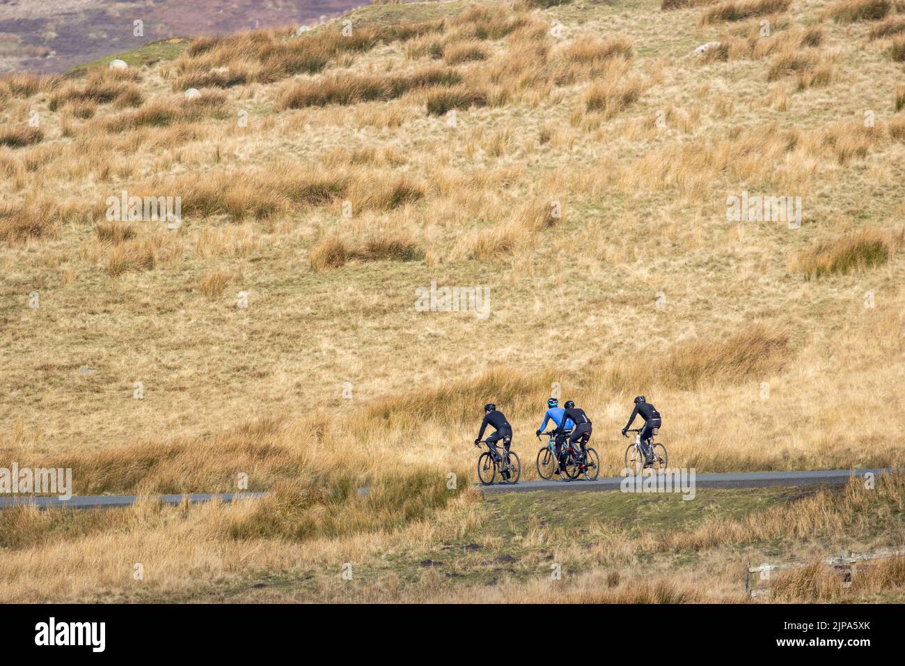 Gruppo di uomini che socializzano sulle bici da strada che guidano le loro bici su una corsia tranquilla di campagna in inverno che indossa l'abbigliamento invernale, Langbar, West Yorkshire, Inghilterra, Foto Stock
